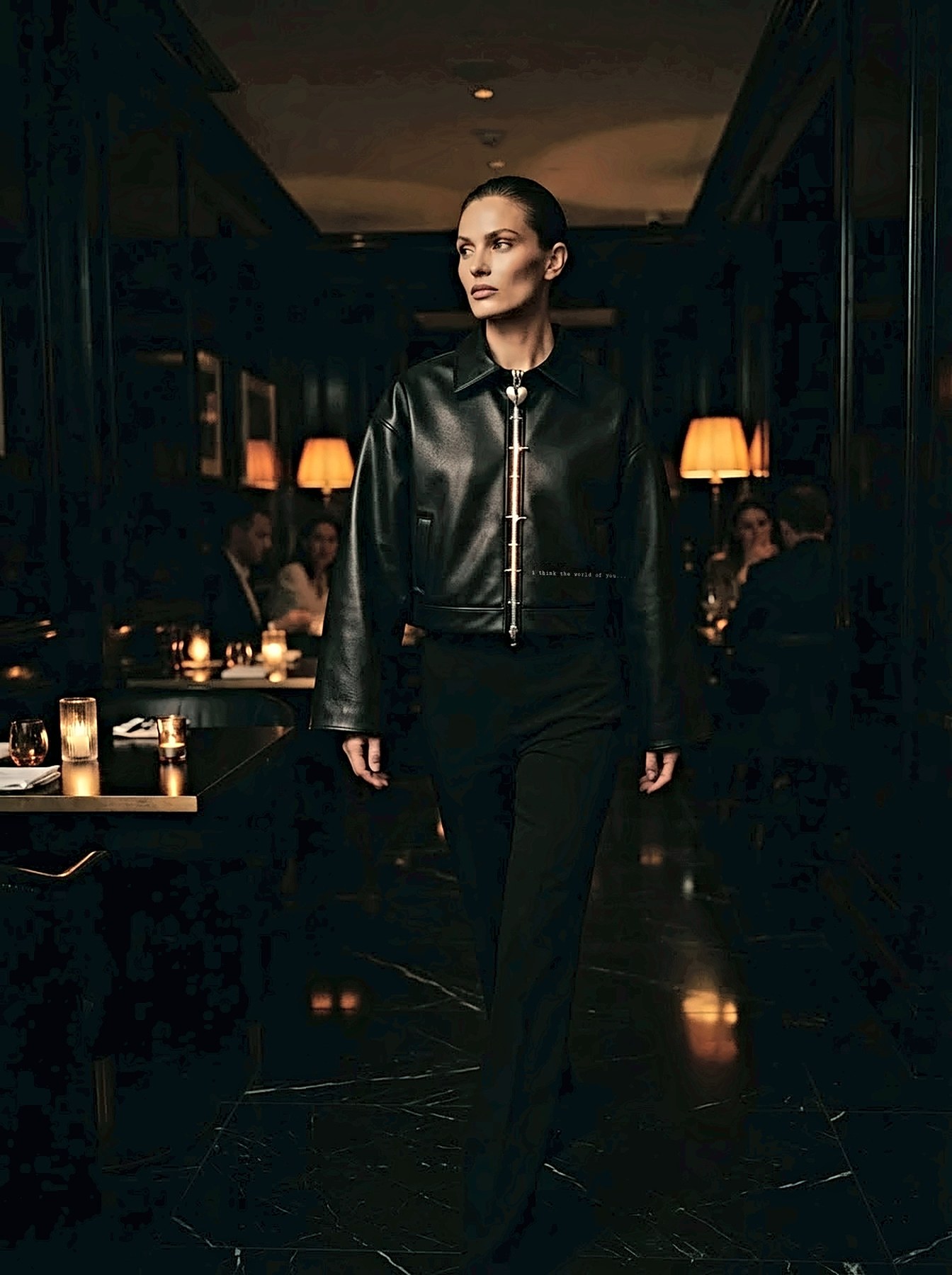 A woman in the Sans Armure jacket in a candlelit dining room